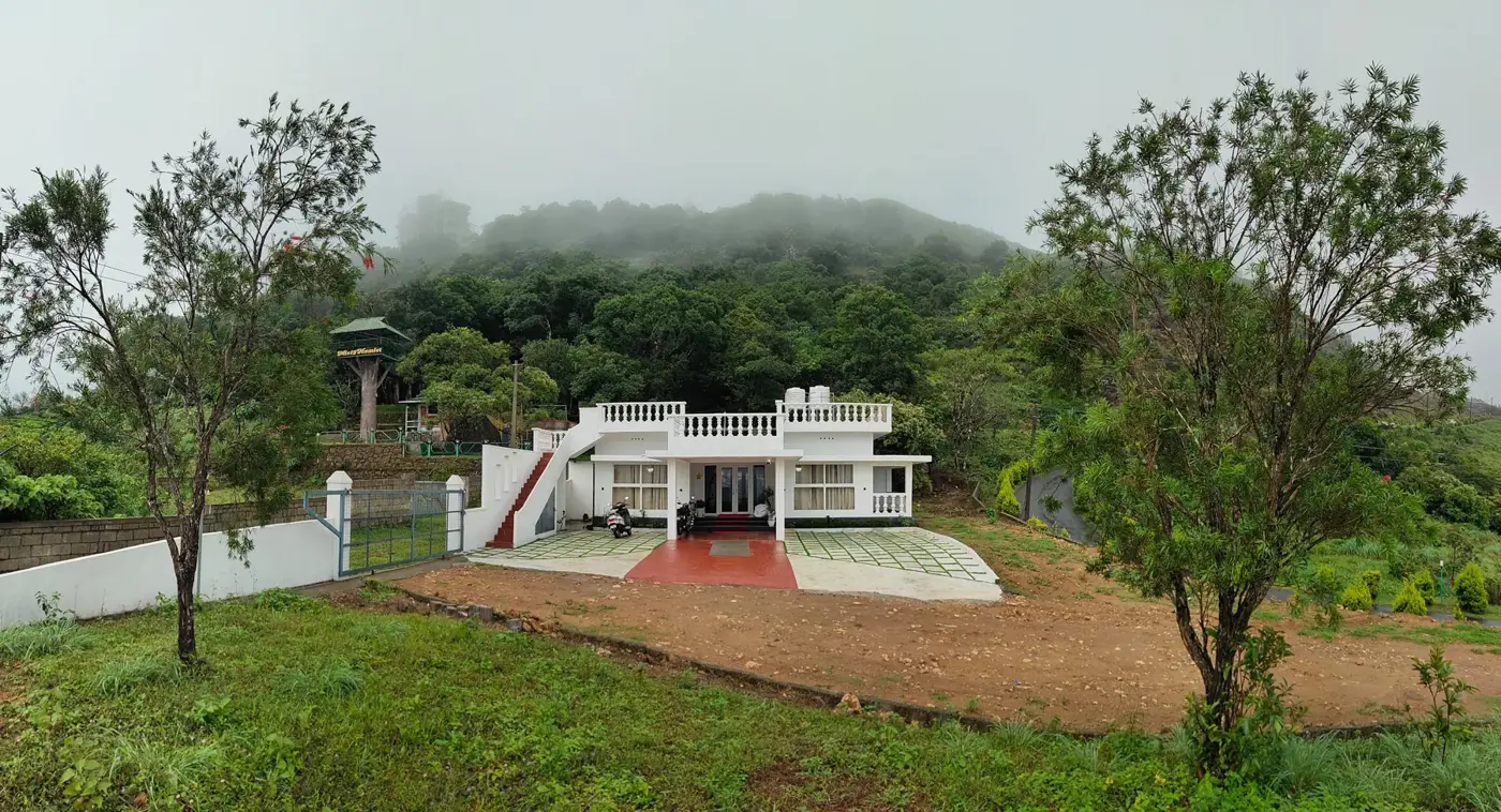 The villa set in green grounds with misty Vagamon hills behind