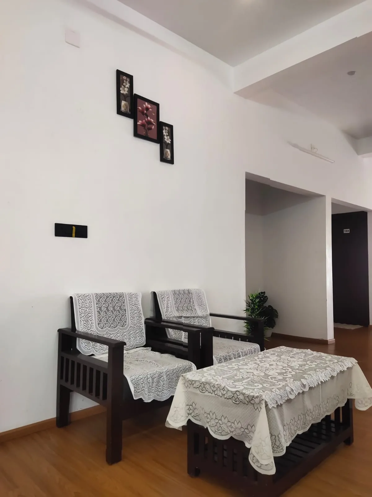 Living room sitting area with wooden chairs and a lace-covered table